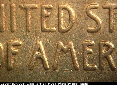 Die-stage B marker on 1909P•1DR•001 showing SE die scratch from T in UNITED through ME in AMERICA.