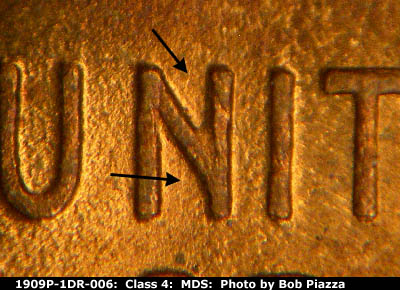 Die-stage B marker on 1909P•1DR•006 showing long and heavy die scratch runs vertically through the middle of the N of UNITED.