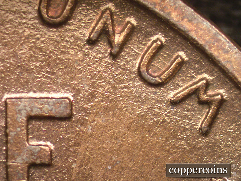 Die-stage A marker on 1909P•1DR•008P showing A die scratch shows running northwest from the lower right corner of the M of Unum as well as other smaller matching….