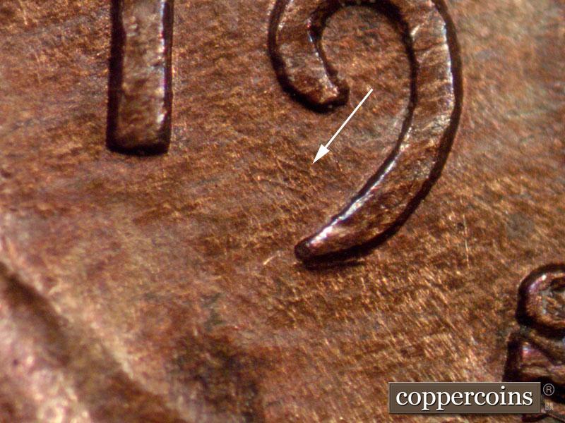 Die-stage A marker on 1910S•1MM•001 showing This image shows northwest to southeast die scratches inside the tail of the nine of the date.