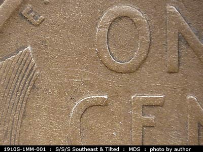 Die-stage B marker on 1910S•1MM•001 showing Mostly east to West die scratches are visible throughout the upper quadrant of the design.