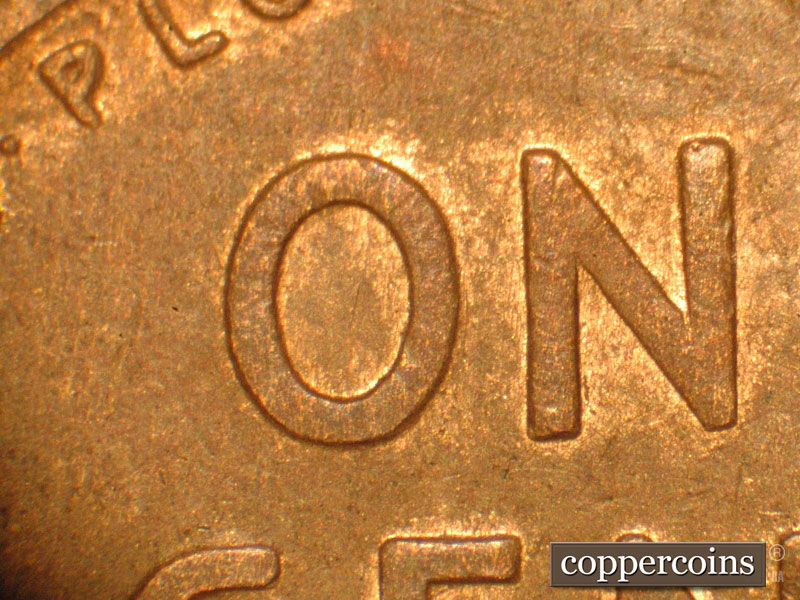 Die-stage B marker on 1910S•1MM•004 showing A number of vertical die scratches are visible in and around the O and N of ONE.