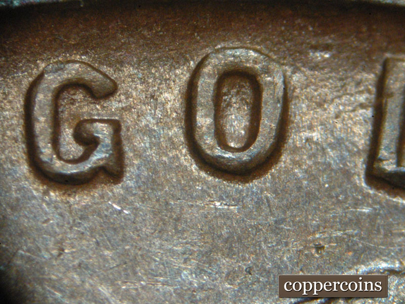 Die-stage C marker on 1911D•1MM•001 showing Die scratch is visible around the O of God.