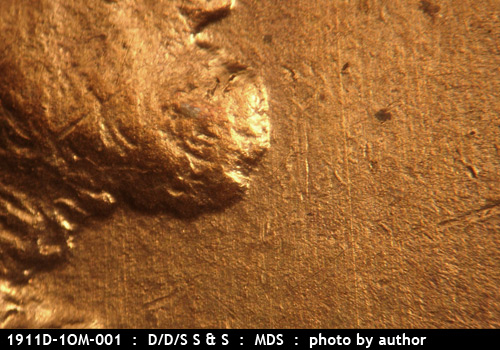 Die-stage B marker on 1911D•1OM•001 showing A patch of long N-S die scratches show in front of the chin and mouth area.