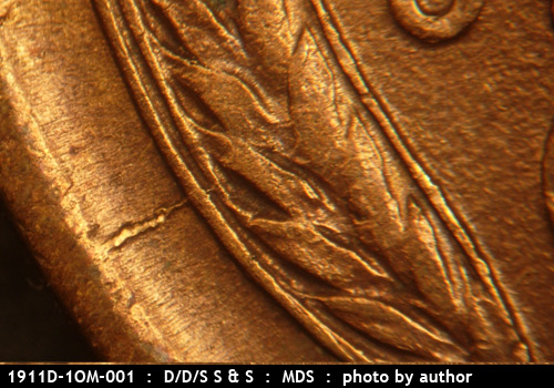 Die-stage B marker on 1911D•1OM•001 showing A heavy rim to grains die crack shows at the lower left area of the left wheat.