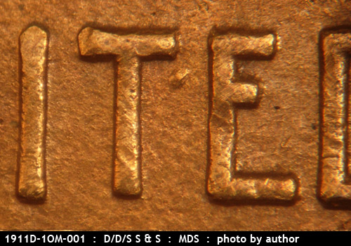 Die-stage B marker on 1911D•1OM•001 showing A heavy die dot shows between the upper T and E of UNITED.