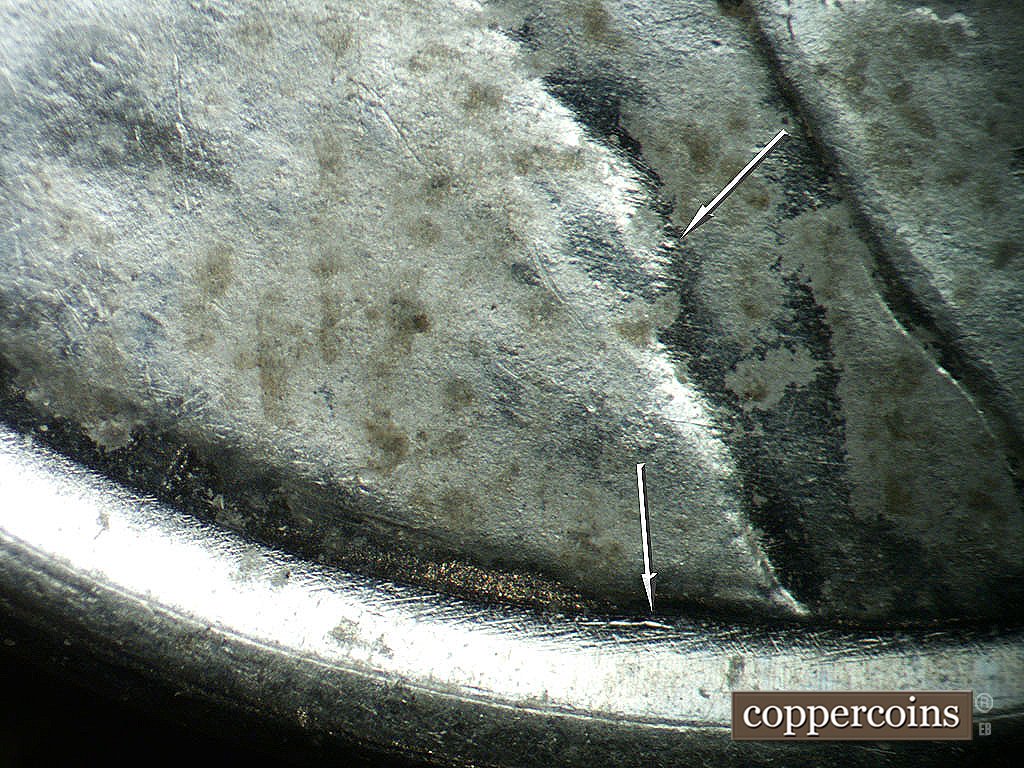 Die-stage B marker on 1943P•1DO•039 showing Die dot in jacket fold, Die scratch in area between rim and bottom of shoulder.
