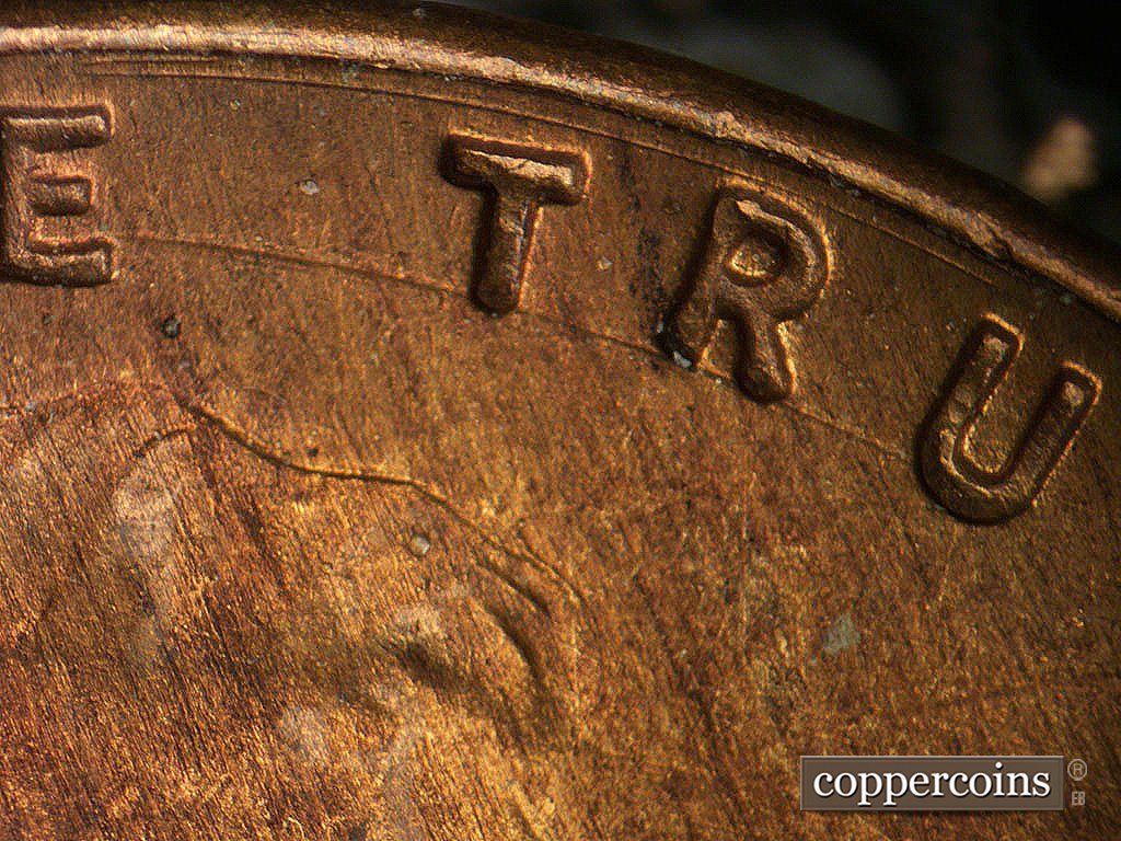 Die-stage B marker on 1946D•1MM•073 showing Concentric die scratch between rim and TRUST, Heavy concentric die scratch along the bottom of TRU in TRUST.