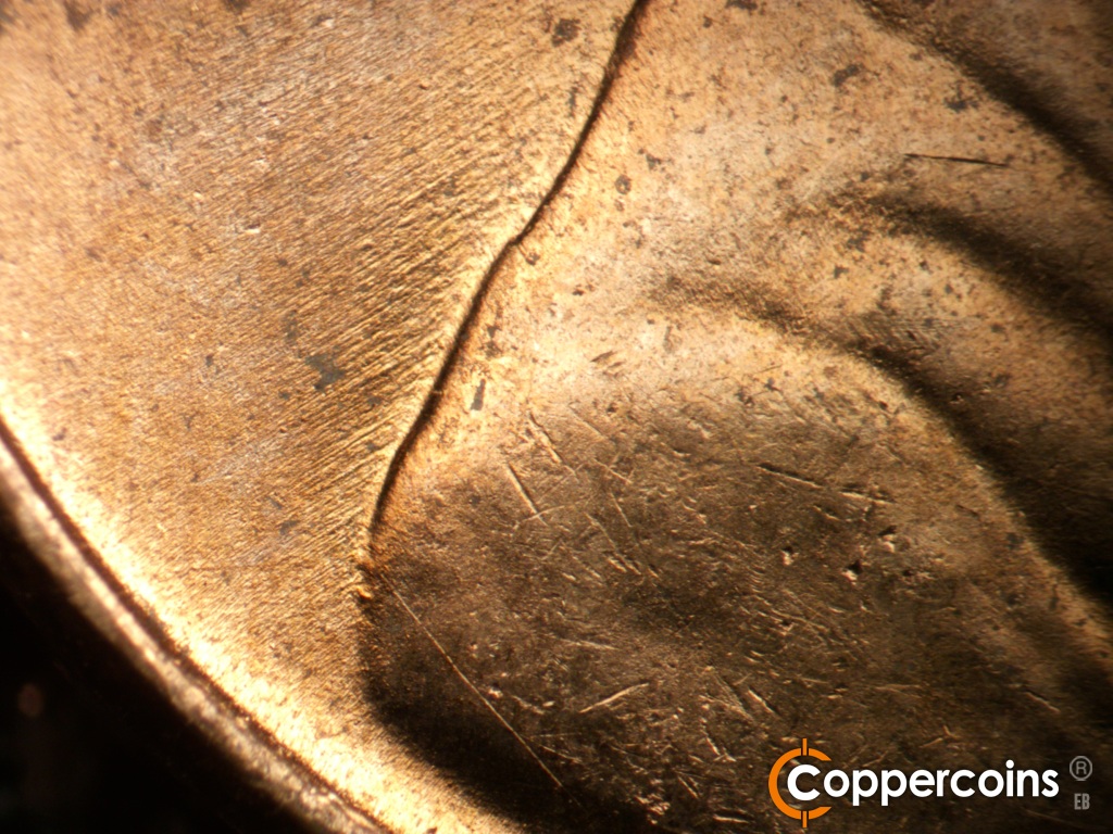Die-stage B marker on 1952D•1MM•088 showing Die gouges from back of shoulder. SW die scratches in field behind jackets.