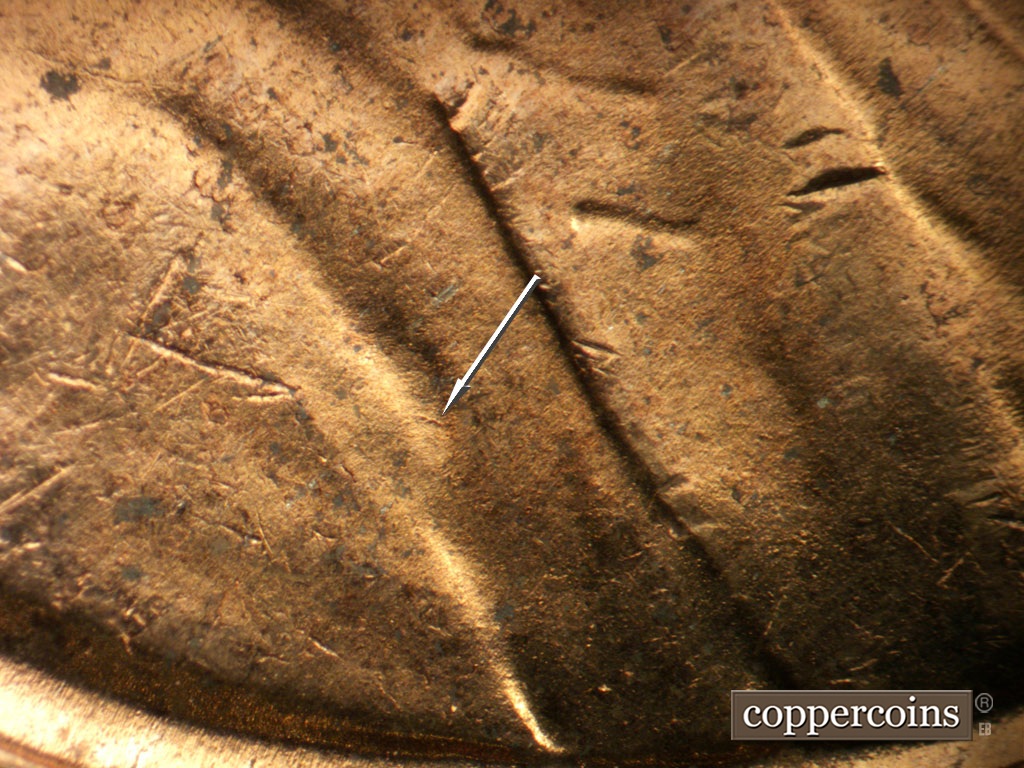 Die-stage B marker on 1953D•1MM•065 showing Short SE die scratch in shoulder fold.