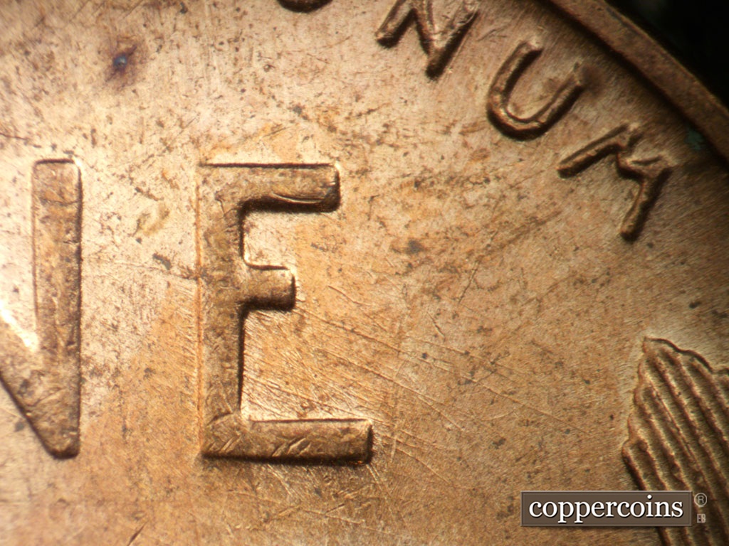 Die-stage B marker on 1955D•1MM•003 showing ESE die scratches from inside lower E in ONE.