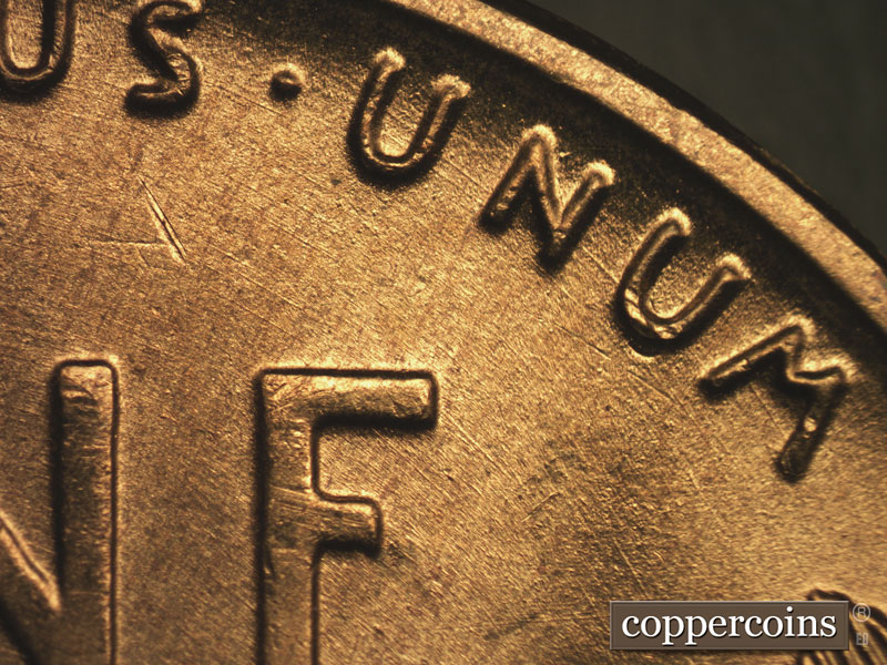 Die-stage B marker on 1955S•1MM•002 showing Concentric die scratches through UNUM.