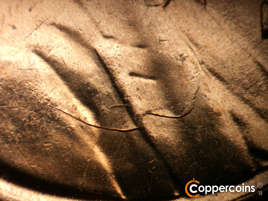 Die-stage D marker on 1955S•1MM•002 showing Heavy die crack across lapel into shoulder.