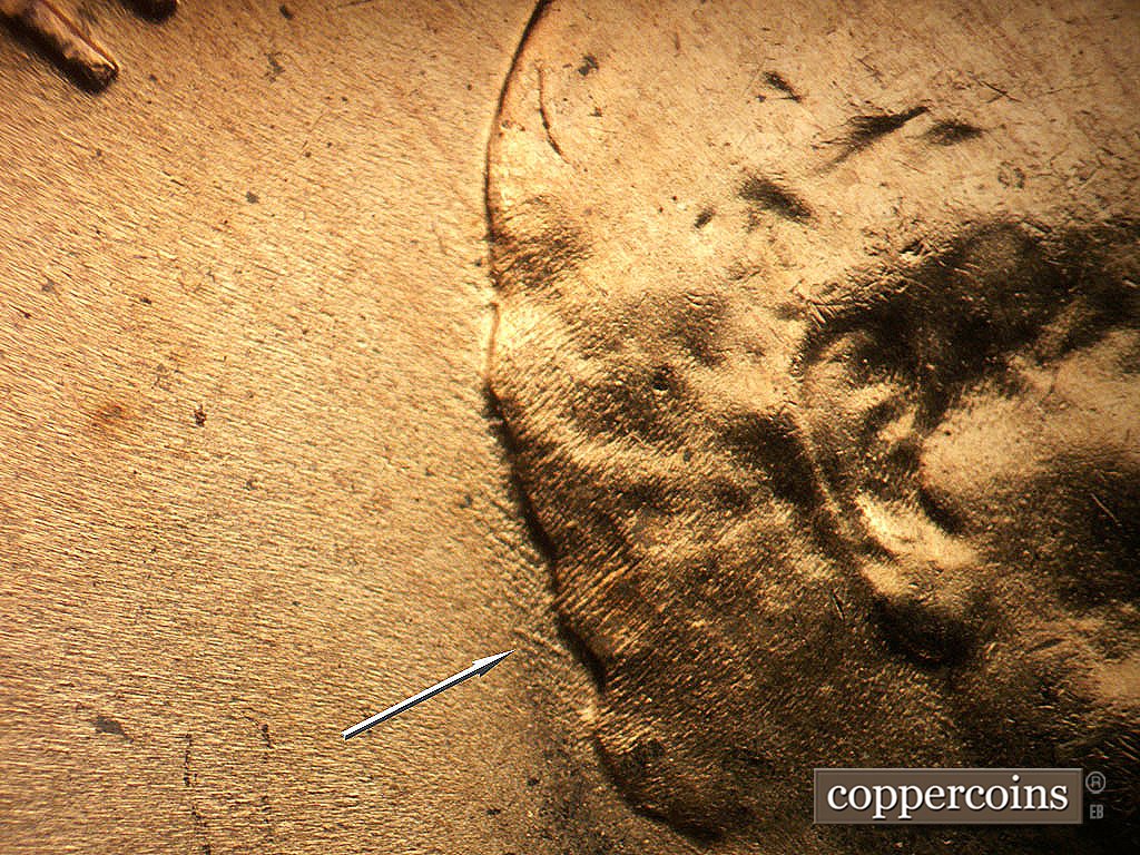 Die-stage B marker on 1956D•1DO•048 showing Short NW die scratches behind hair.