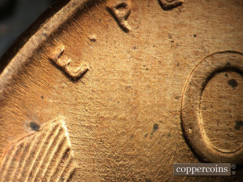 Die-stage A marker on 1956D•1MM•062 showing Worn E/W die scratches across reverse.