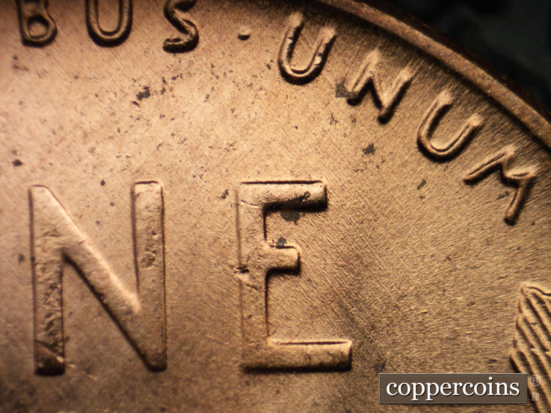 Die-stage B marker on 1956D•1MM•062 showing SE die scratches east of E in ONE.