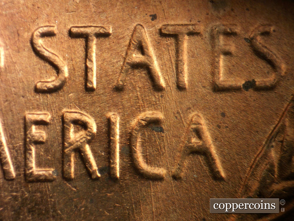 Die-stage B marker on 1956P•1DO•008 showing Generally N/S die scratches through AT in STATES through CA in AMERICA.