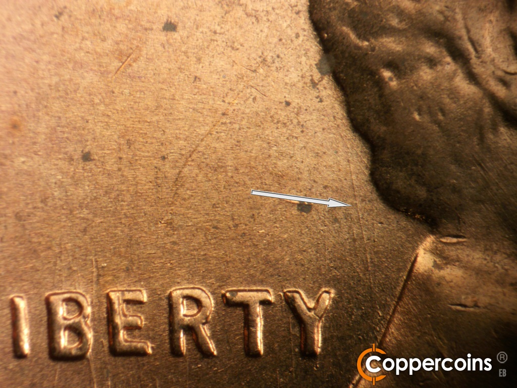 Die-stage B marker on 1957D•1MM•104 showing NNW die scratch from back of collar to back of hair.