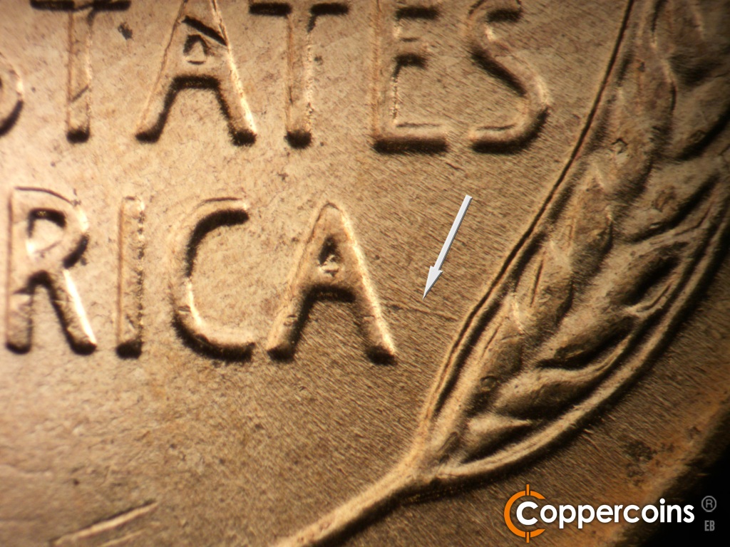 Die-stage B marker on 1957D•1MM•107 showing ESE die scratch connect last A in AMERICA to lower right wheat stalk.