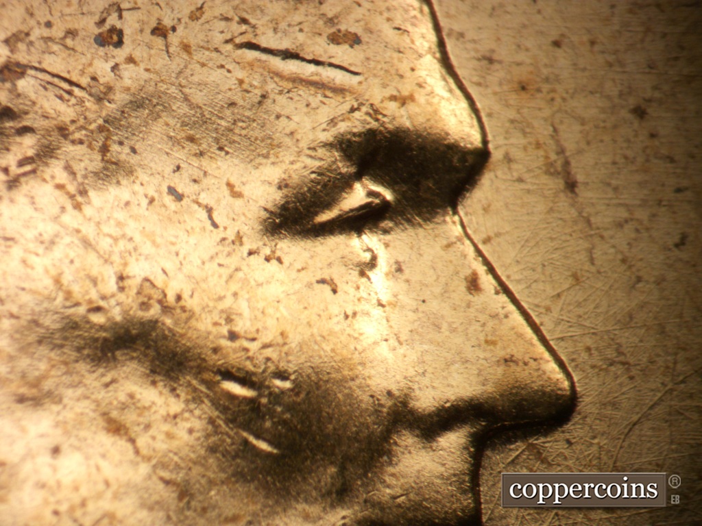 Die-stage B marker on 1957P•1DO•007 showing Extra lower eyelid north of primary. Die scratches on temple.