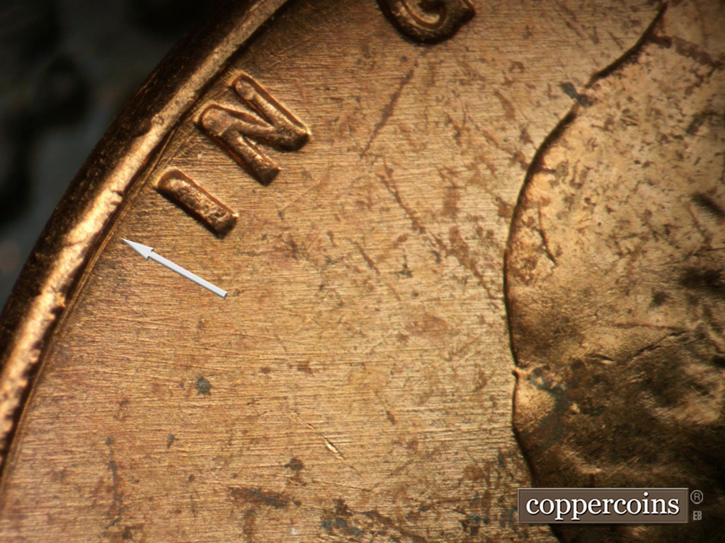 Die-stage A marker on 1957P•1DO•007 showing Concentric die scratch between rim and IN.E/W die scratch in field behind head.