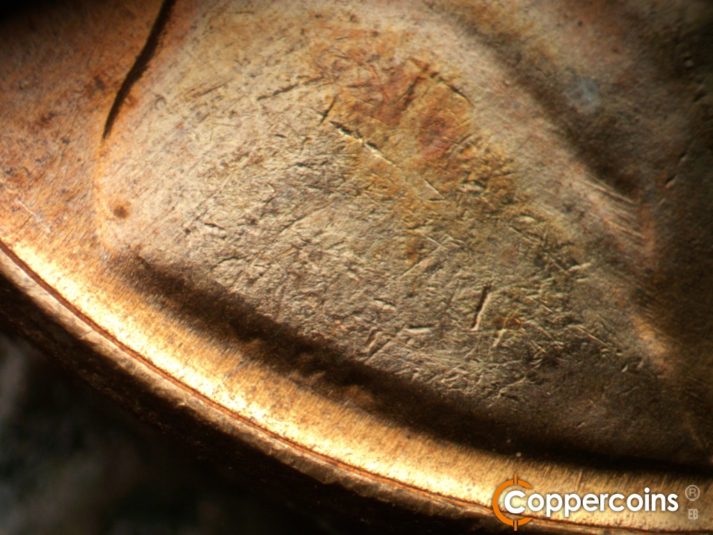 Die-stage B marker on 1958D•1MM•112 showing ESE die scratches in shoulder fold.