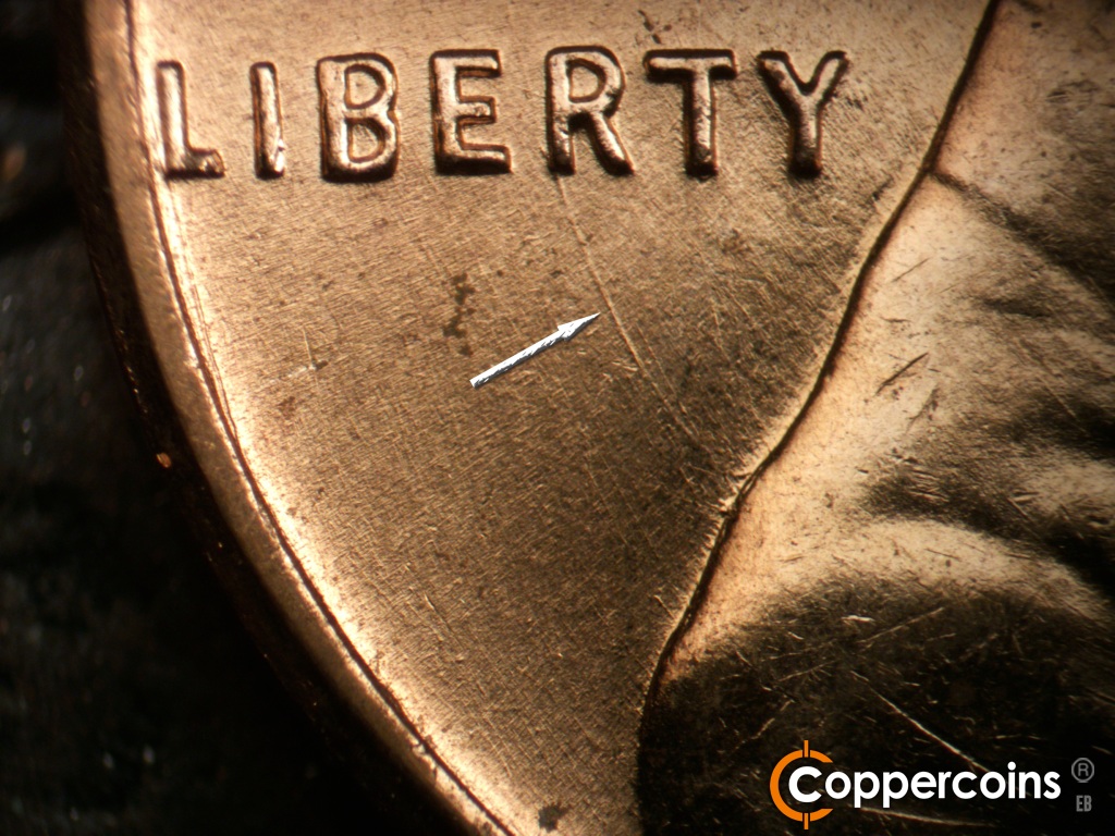Die-stage B marker on 1959D•1MM•129 showing Concentric die gouge from back of shoulder to R in LIBERTY.
