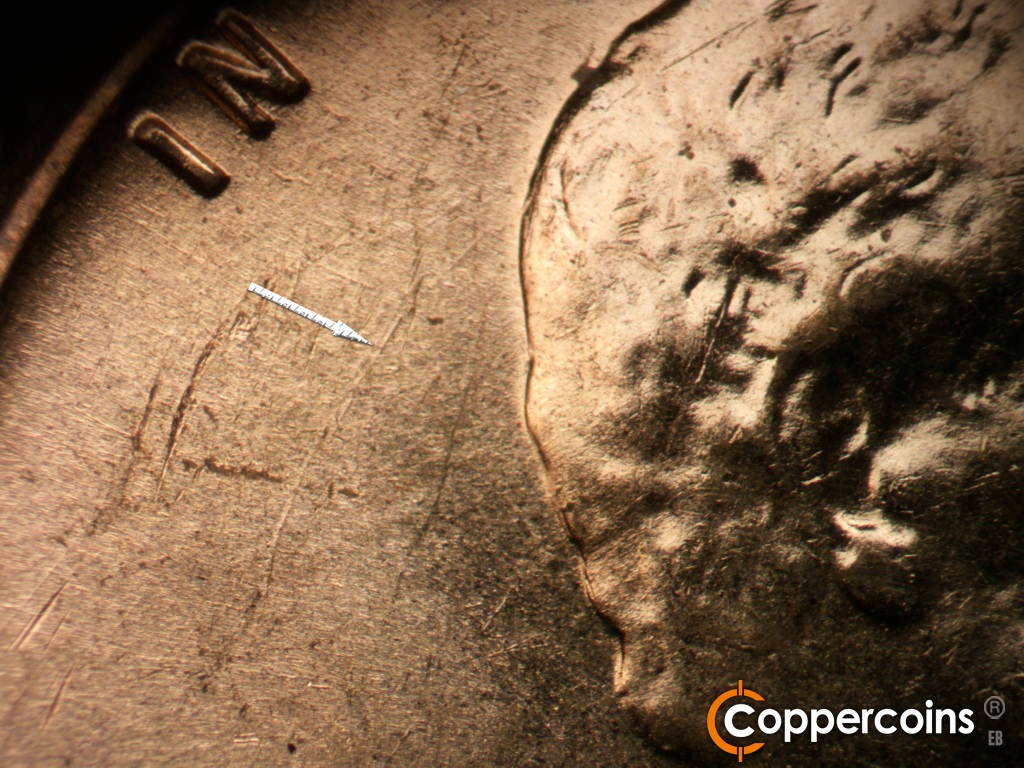 Die-stage B marker on 1959D•1MM•129 showing Die gouge in field behind hair.