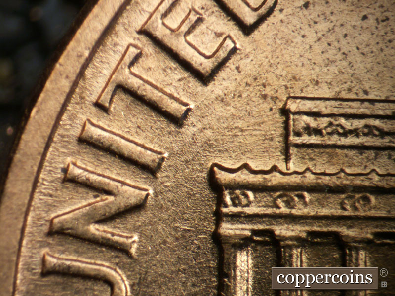 Die-stage B marker on 1960D•1DO•001 showing Light E/W die scratches from left roof toward T in UNITED.