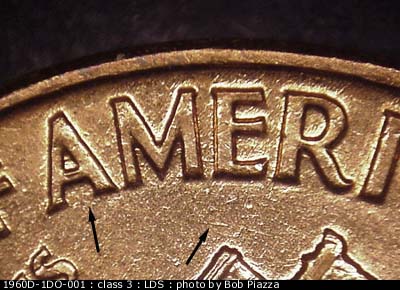 Die-stage C marker on 1960D•1DO•001 showing A die scratch connects the lower M and E of AMERICA. Another die scratch runs NW-SE to the right of the right roof top.