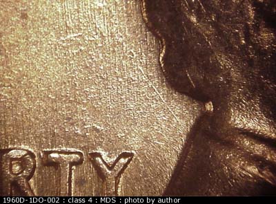 Die-stage B marker on 1960D•1DO•002 showing A single NE die scratch protrudes from the back of the collar.