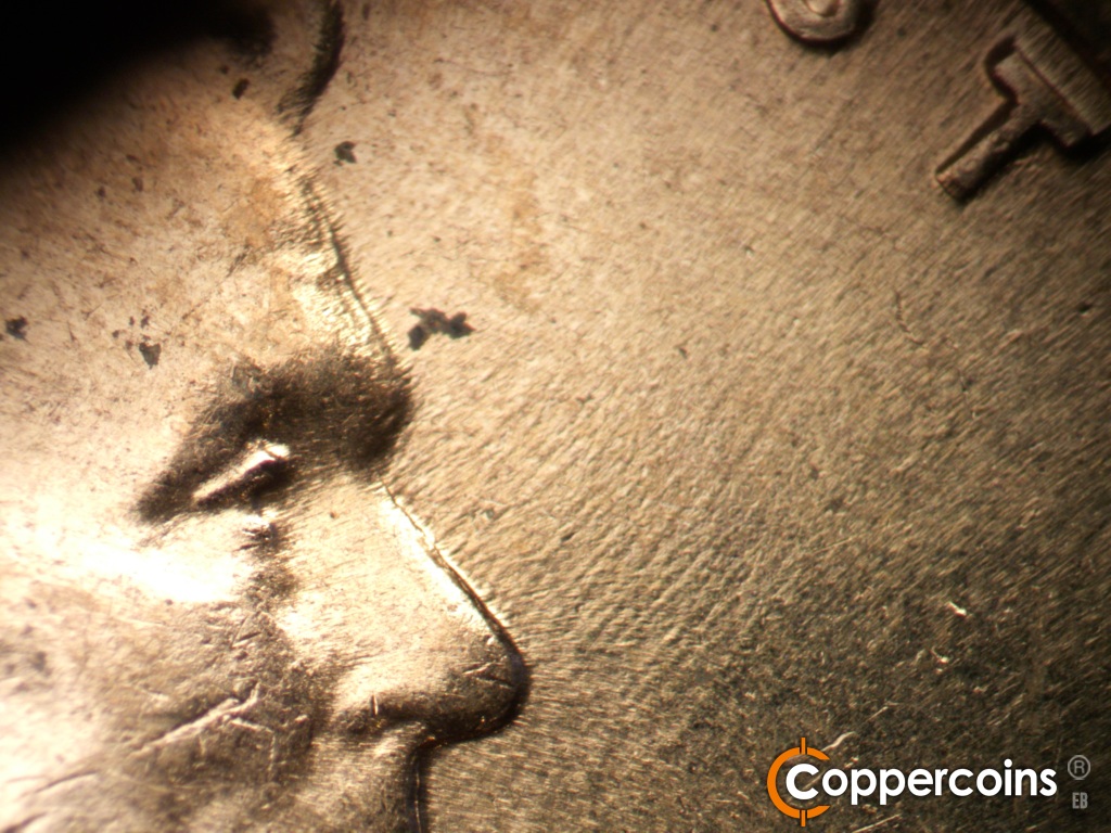 Die-stage C marker on 1960D•1DO•007 showing Worn NE die scratches from nose toward TRUST.