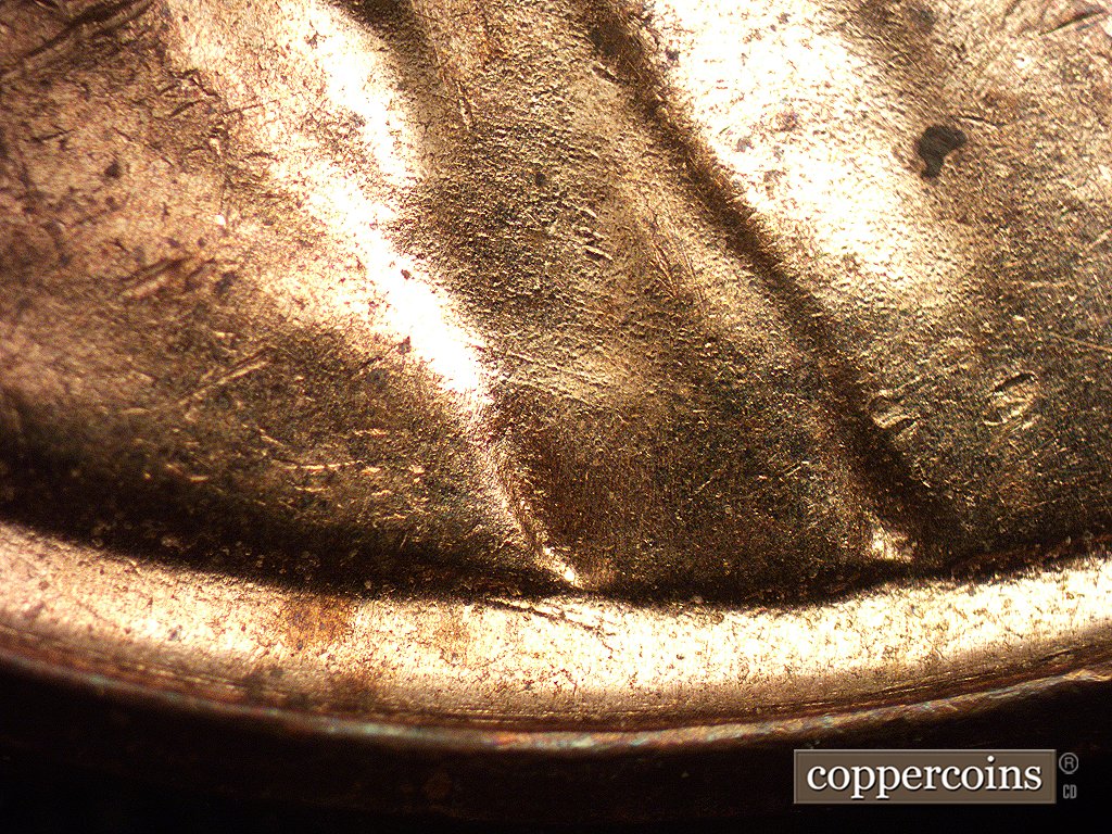 Die-stage A marker on 1960D•1MM•001 showing Die scratches run SE from the shoulder fold area.