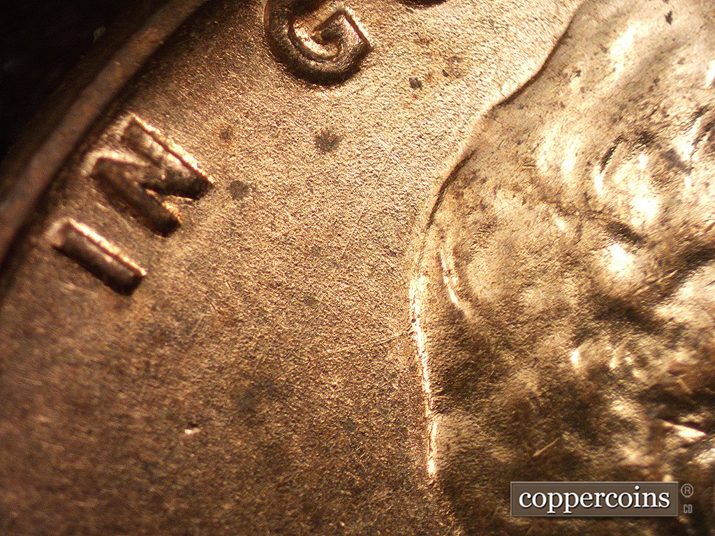 Die-stage A marker on 1960D•1MM•001 showing A die scratch runs west from the head. Another die scratch SW-NE in the field beneath the G of GOD.