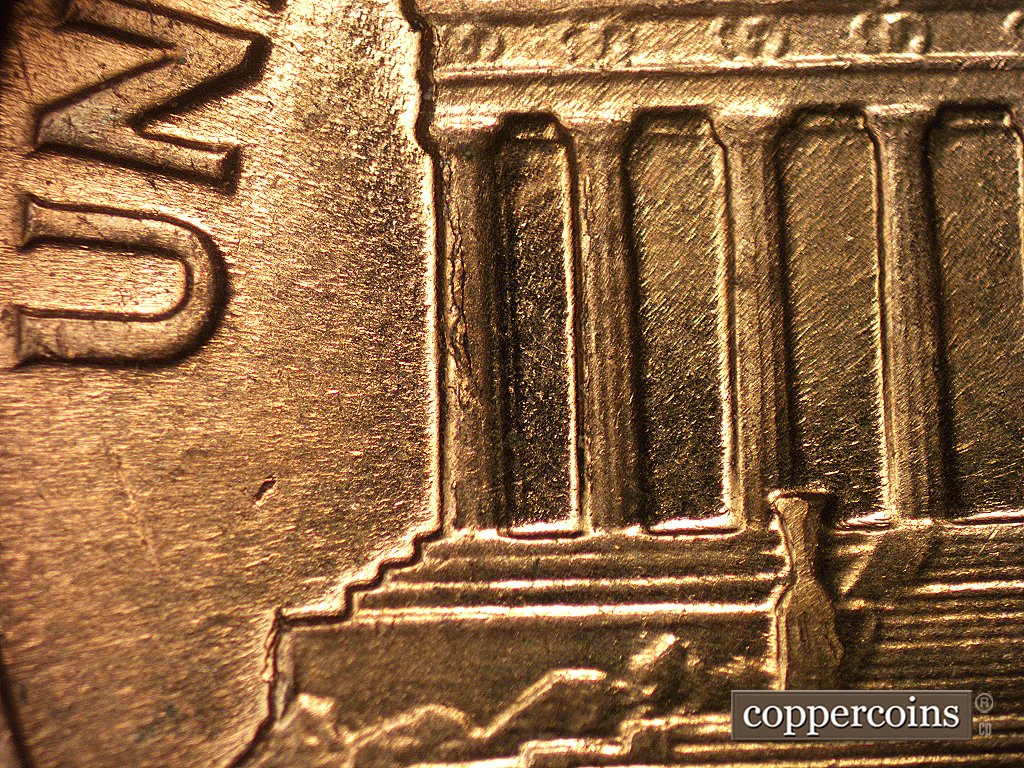 Die-stage D marker on 1960D•1MM•003 showing A large die crack shows on column 1 and a smaller die crack shows on column 2.