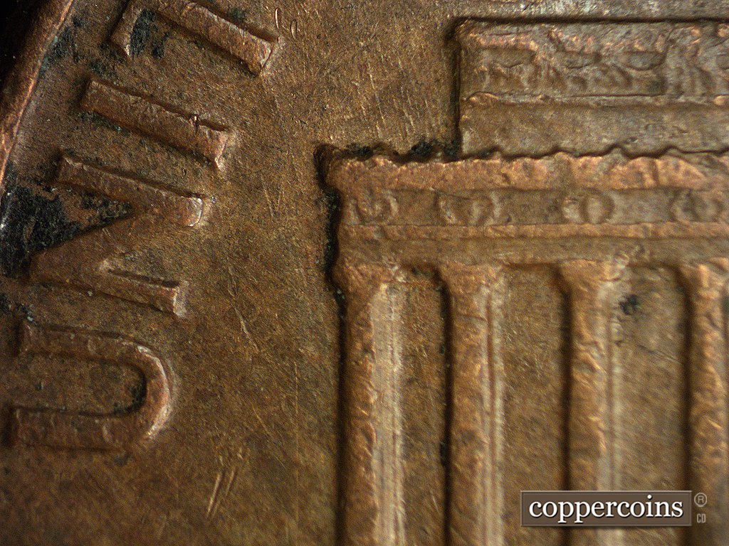 Die-stage A marker on 1960D•1MM•003 showing Near vertical die scratches in the field to the left of the building.