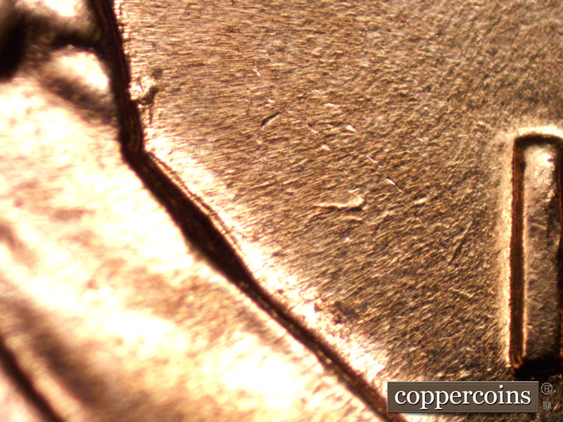 Die-stage B marker on 1960D•1MM•004 showing Die gouge between front of lapel and 1 in date.