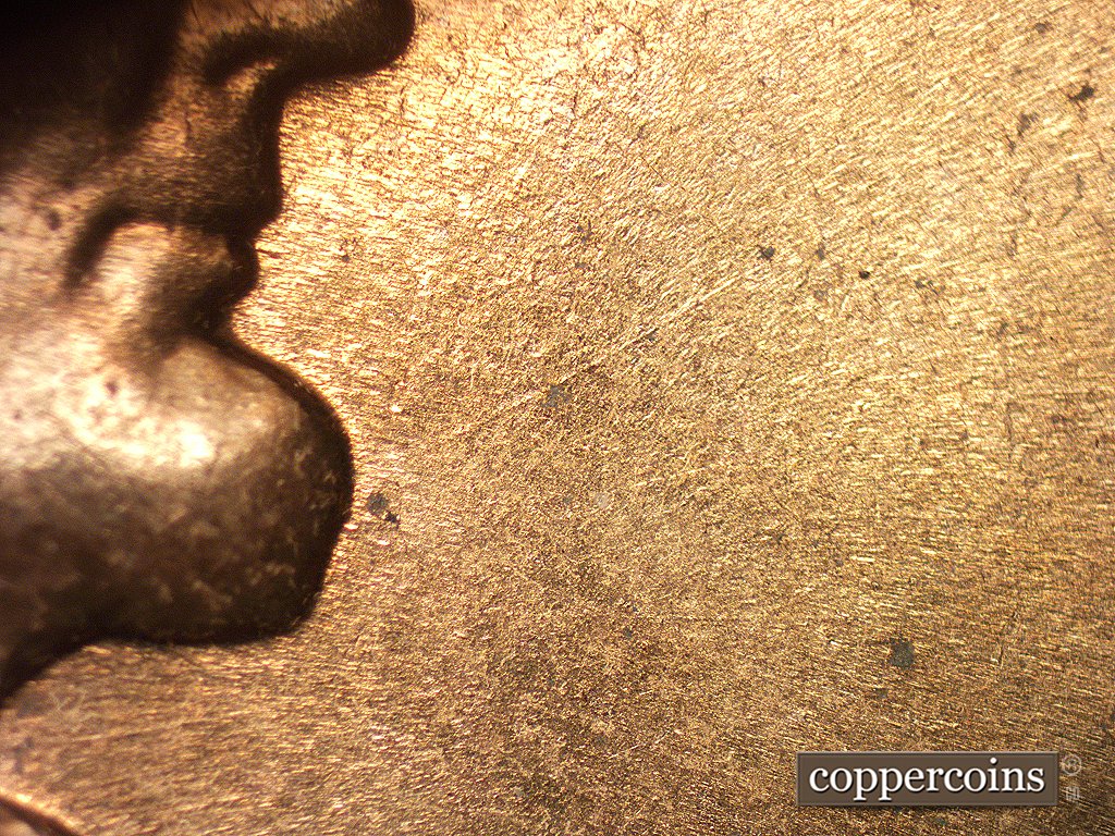 Die-stage B marker on 1960D•1MM•005 showing Die scratch NE from chin.