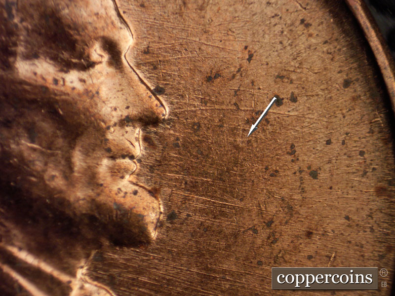 Die-stage D marker on 1960D•1MM•006 showing E/W die scratches in front of face, die depression in fron of mouth.