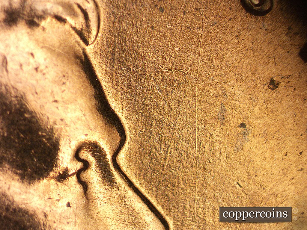 Die-stage C marker on 1960D•1MM•006 showing Some old and some fresh die scratches in front of the forehead.