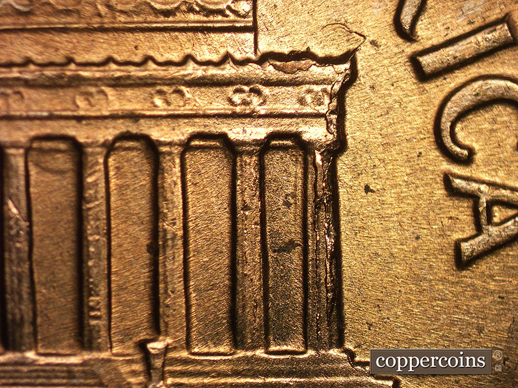 Die-stage C marker on 1960D•1MM•006 showing A large die crack shows on column 12 running into the cornice. A depression shows in the field on top of the eave. A….