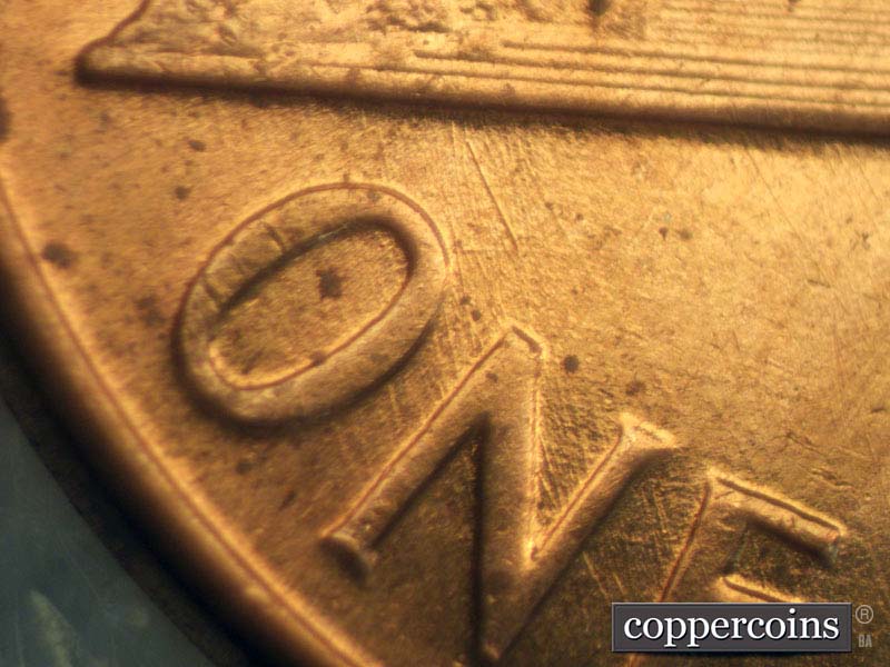 Die-stage B marker on 1960D•1MM•007 showing NW die scratches through ONE.