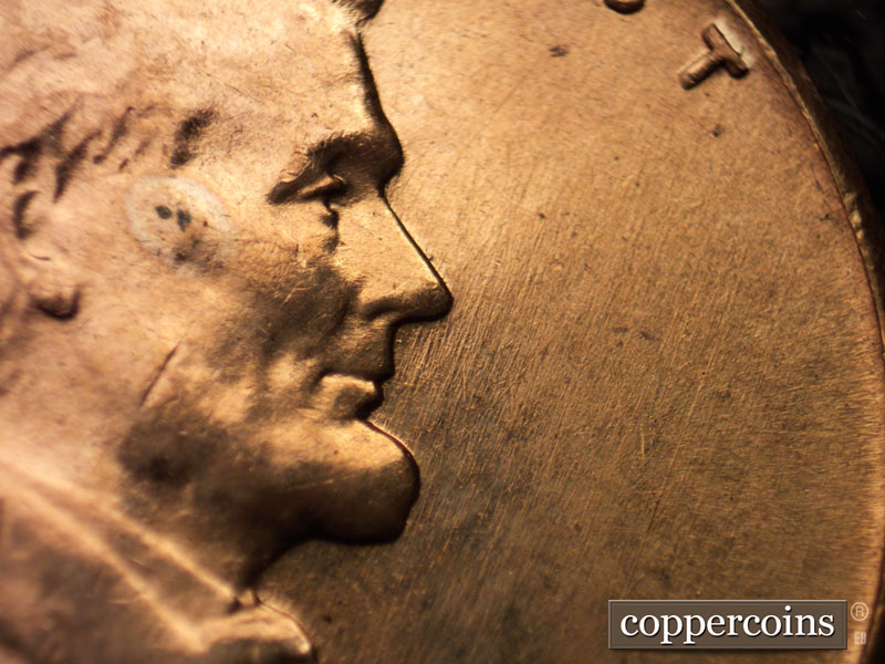 Die-stage B marker on 1960D•1MM•008 showing NE die scratches in front of face.