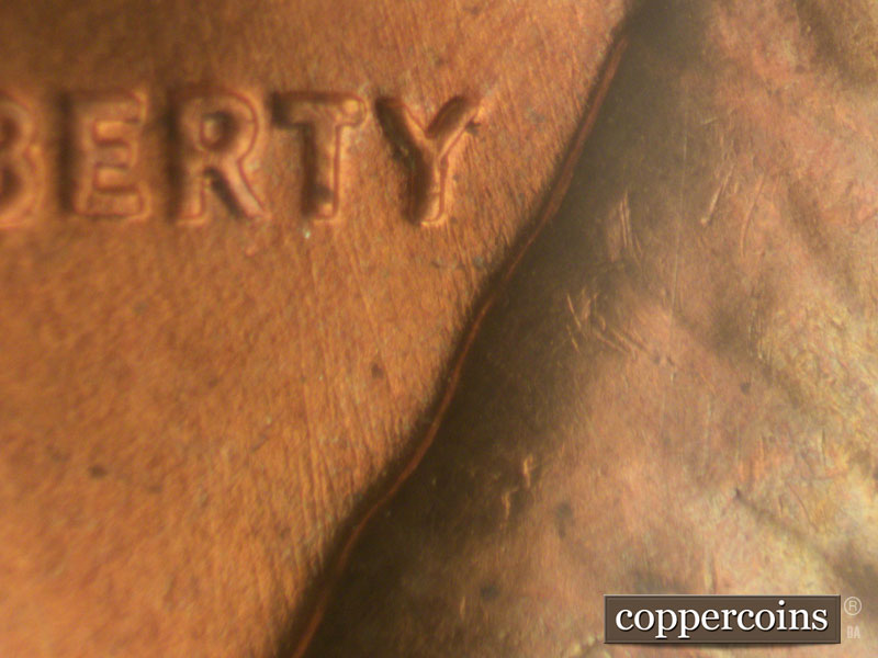 Die-stage B marker on 1960D•1MM•009 showing Light NNW die scratches from back of shoulder toward LIBERTY.