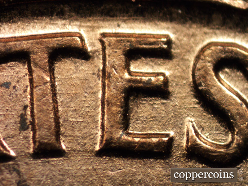 Die-stage A marker on 1960D•1MM•015 showing E/W die scratches through ATES in STATES.