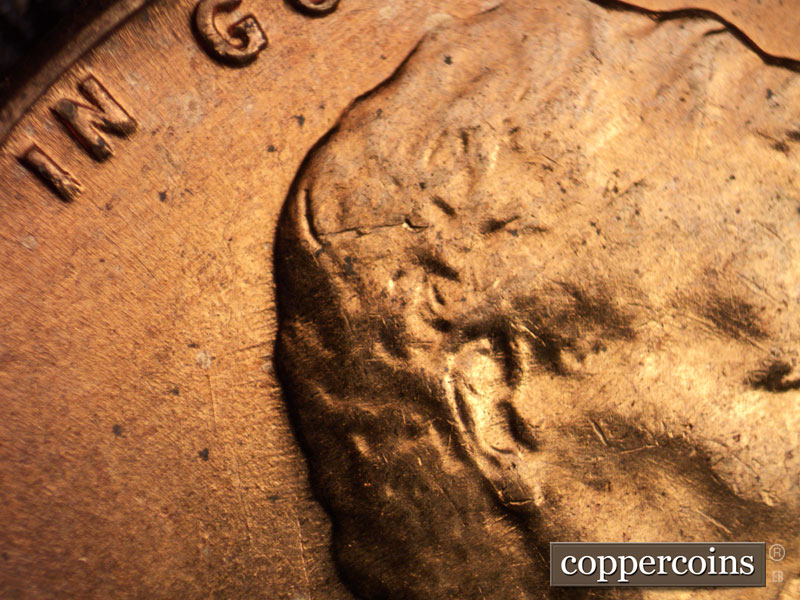 Die-stage B marker on 1960D•1MM•017 showing Long die crack from ear NE to top of head.