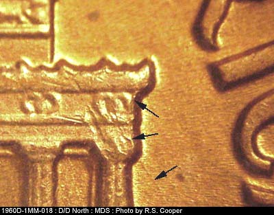Die-stage B marker on 1960D•1MM•018 showing Die chips on right cornice with a die crack on top of column #12. A fading die scratch is still visible from upper co….