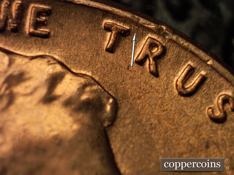 Die-stage B marker on 1960D•1MM•020 showing Die gouge between TR in TRUST and rim.