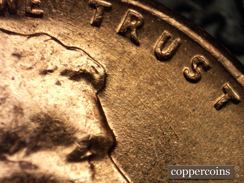 Die-stage B marker on 1960D•1MM•025 showing Concentric die scratching in area between TRUST and forehead.