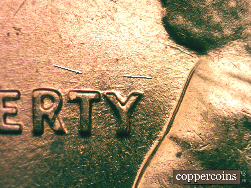 Die-stage B marker on 1960D•1MM•027 showing A die scratch runs NE from the T and Y of LIBERTY.